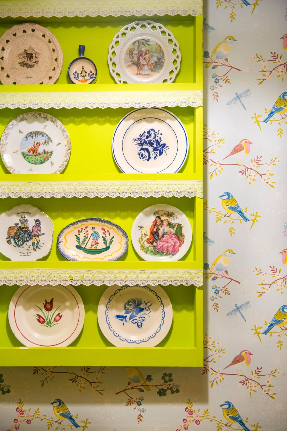 Une collection d’assiettes exposée sur les étagères vertes de Tours
